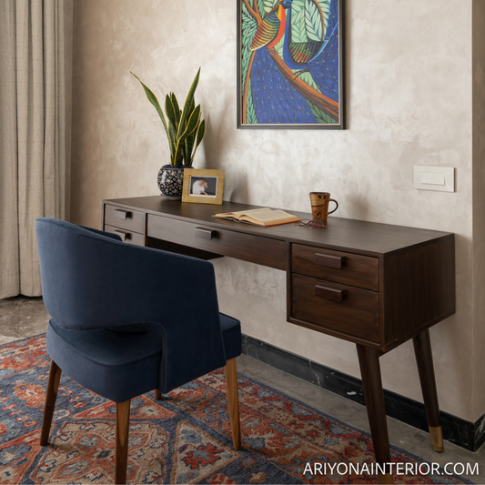 Wooden desk with a blue chair in a room with a colorful rug and wall art.