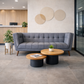 Gray sofa in a modern office lobby with round tables and plants.