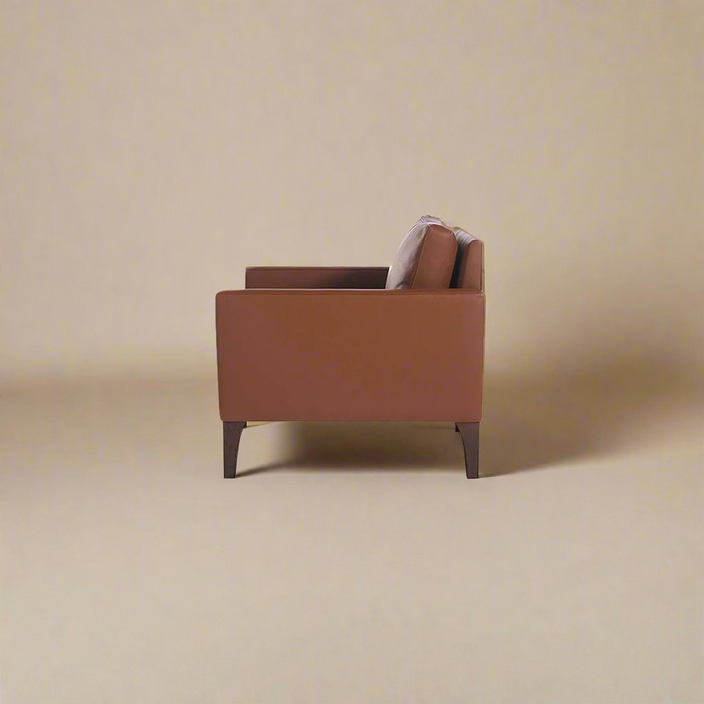 Cyrene W contemporary faux leather single seater sofa with wooden legs in warm tan upholstery side view
