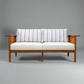 Hibiki Japanese minimalist teakwood sofa with upholstered seat and back cushions and signature side leather panel detail – front view with cushions